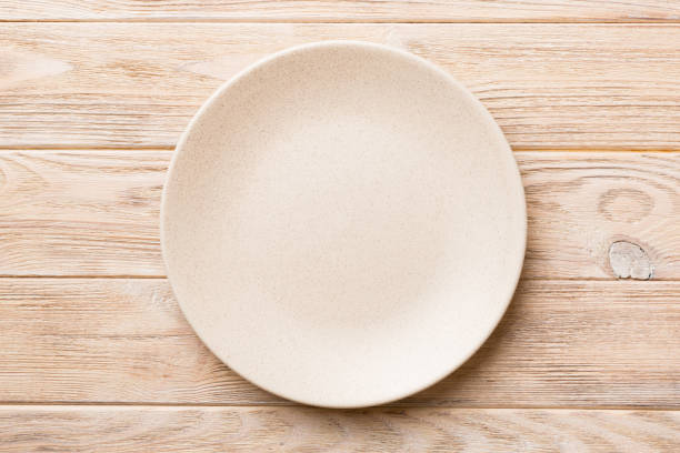 istock Top view of empty light plate on wooden background. Empty space for your design 1439537716