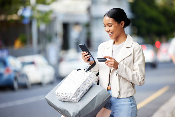 Happy woman with her phone, credit card and bag after shopping in the city. Young latin female carrying bags, spending money, looking for sales and enjoying online eCommerce store sale with a smile Happy woman with her phone, credit card and bag after shopping in the city. Young latin female carrying bags, spending money, looking for sales and enjoying online eCommerce store sale with a smile spending money stock pictures, royalty-free photos & images