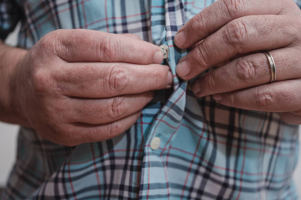 istock Close-up of a man's hands buttoning a plaid shirt. 1439537879