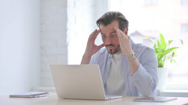 istock Angry Young Man Working on Laptop in Office 1439541305