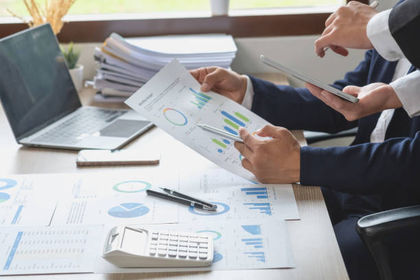 istock Team of business use calculators and graph analysis computer laptop tablets to plan marketing strategies and make profitable investments for the company. 1439542471