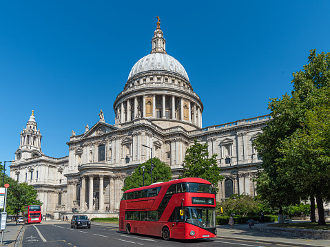 St Paul's Cathedral with a red double decker bus and a cab in the City of London on a sunny day
