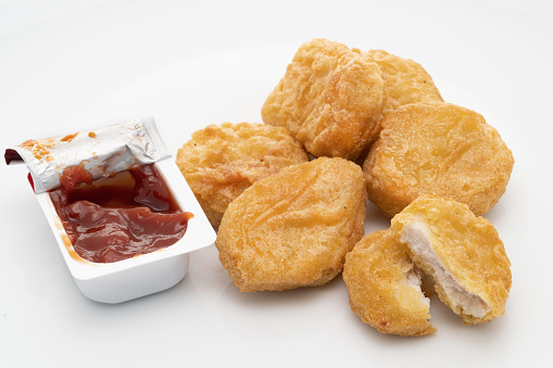 Crispy chicken nuggets with a tomato ketchup sachet - white background