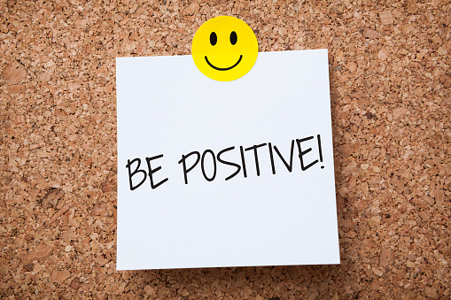 White Sticky Note With Be Positive And Red Push Pin On Cork Board
