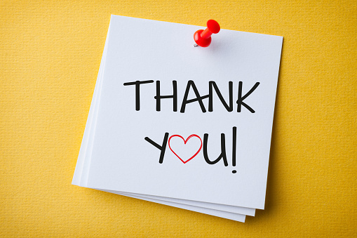 White Sticky Note With Thank You And Red Push Pin On Yellow Cardboard