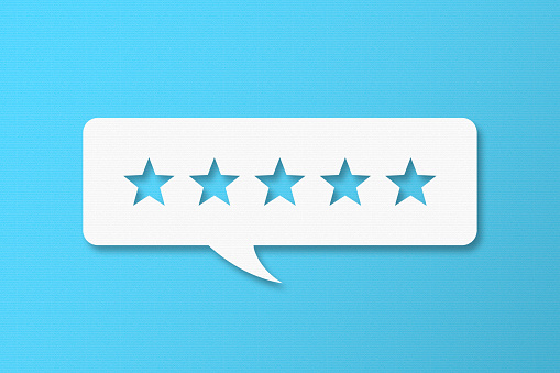 Feedback Concept - White Chat Bubble With Cut Out Star Shapes On Blue Cardboard Background