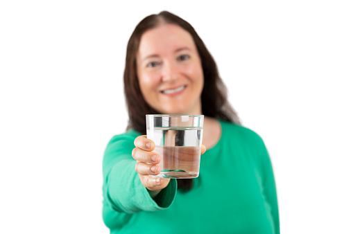 Beautiful woman smiling while holding a glass of water with white background. Lifestyle concept.