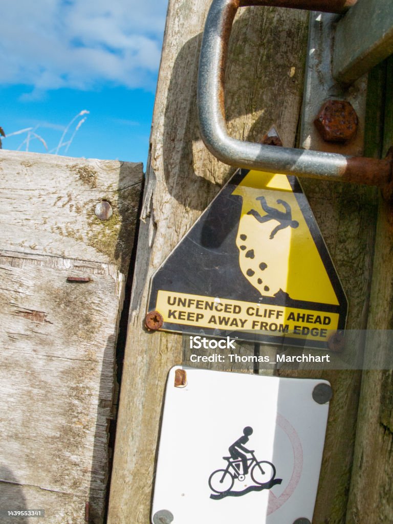 Sign unfenced cliff Warning sign for an unfenced cliff on the south west coast path between Port Isaac and Polzath in Cornwall, UK. Beach Stock Photo