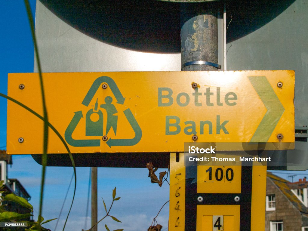 Sign to a bottle bank Yellow sign, showing the directon to the next bottle bank in Port Isaac in Cornwall, UK Blue Stock Photo