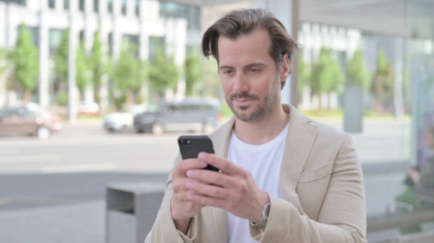 istock Young Man Browsing Internet on Smartphone Outdoor 1439562942