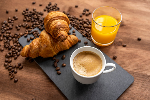 hot coffee and two croissants and orange juice on a wooden table background, selective approach.