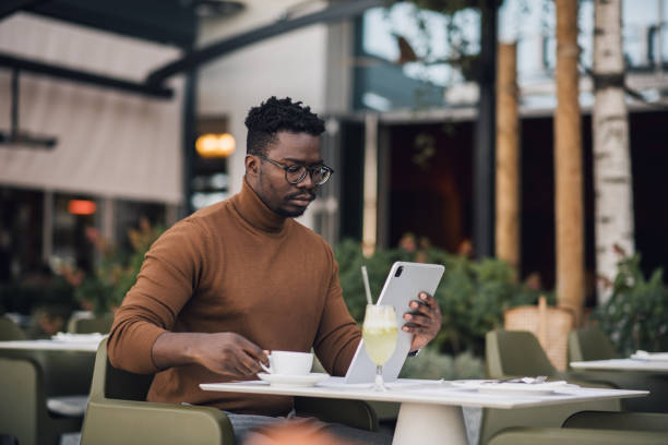 istock Young black businessman working on a tablet and drinking coffee 1439571117