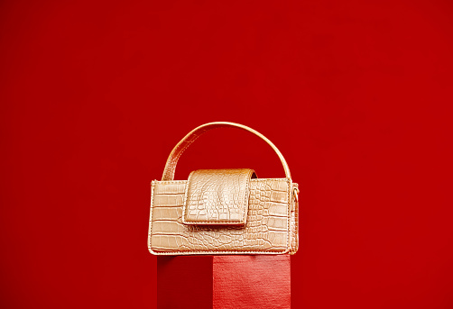 Gold purse on a red plinth with a red background for copy space