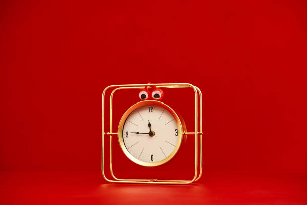 Gold clock with googly eyes against a red background with space for text