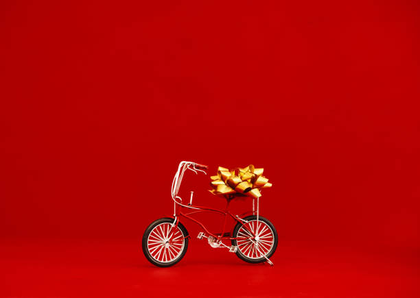 Small red bike with gold gift bow against a red background with space for text