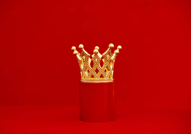 istock Decorative gold crown on a red plinth. Red background with copy space 1439573405