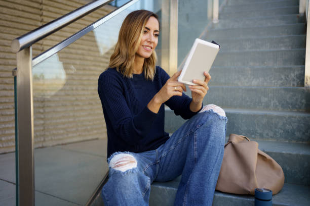 istock Glad woman enjoying reading on steps 1439576091