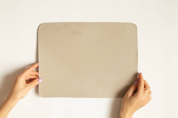 istock Female hands hold a gray cardboard on a white background, space for text 1439576554