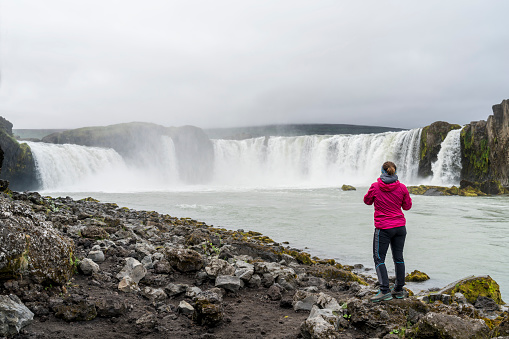 One women standing at Goðafoss waterfall in Northern Iceland on cloudy day