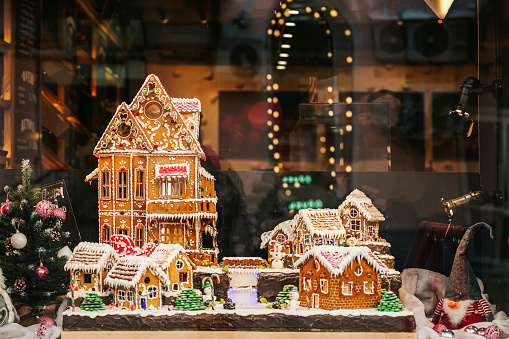 Gingerbread houses in urban holiday showcase, evening lights, reflections. Christmas concept