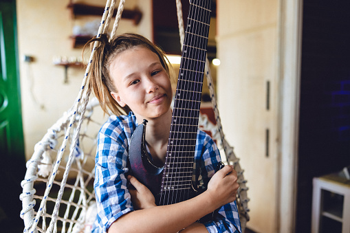 Young multiracial girl posing for a portrait photo with her electric guitar.
