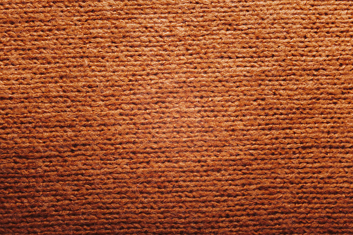 Autumn concept - background of knitted wool brown sweater. Knit fabric texture. Close up view. Knitted background, horizontal stripes