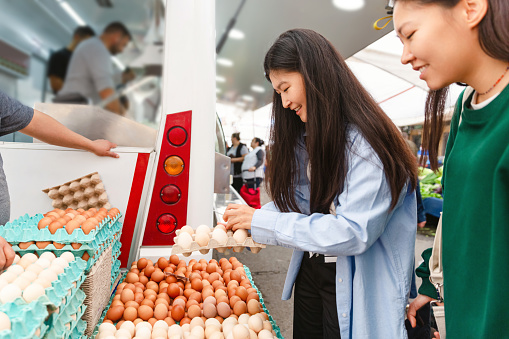 Women selecting fresh eggs on market, everything is fresh and organic