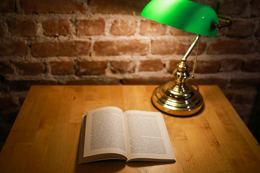 An open book and green table lamp background brick pattern. book reading concept