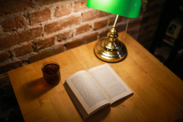 An open book, filter coffee cup and green table lamp background brick pattern. book reading concept