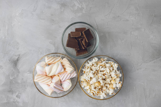 istock Popcorn, marshmallow, chocolate bar pieces in bowls. Ingredients for cooking, copy space 1439596270