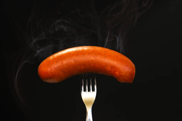 istock hot sausage on a fork on a black background. Close-up 1439600883