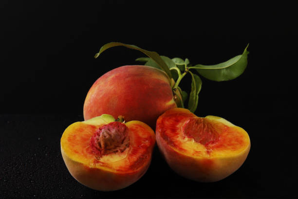 istock Ripe peaches in a cut with a branch under dark lighting. Close-up 1439604112