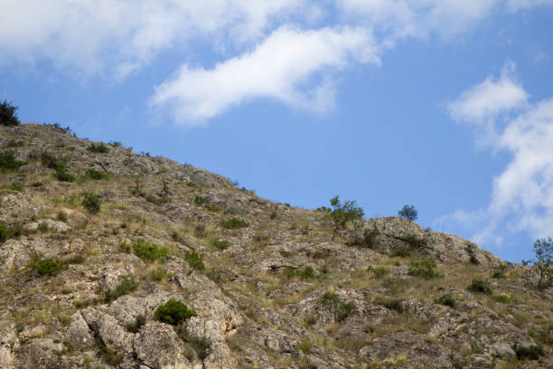 istock Sloping rocky hill in front of cloudy blue sky 1439607787