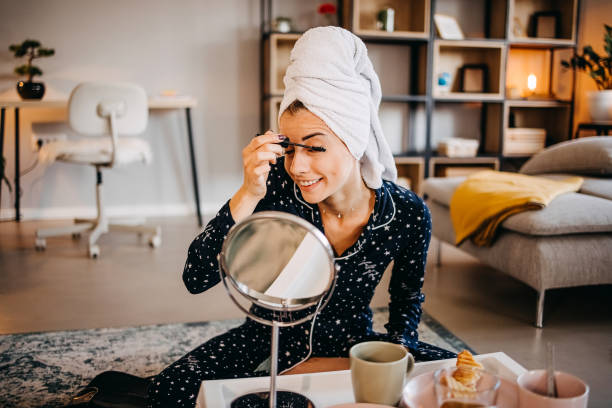 istock Beautiful young woman applying make up 1439608588