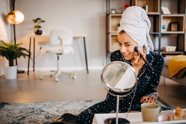 istock Beautiful young woman applying make up 1439608591