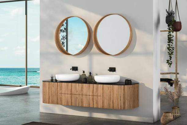 istock Modern bathroom interior with concrete floor, two sinks, double mirrors, white bathtub, interior plants, sea view from window.Minimalist bathroom with modern furniture and panoramic view. 3D rendering 1439609426