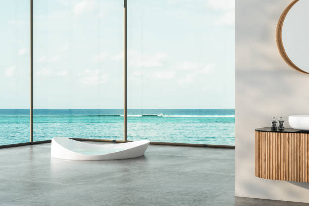 istock Modern bathroom interior with concrete floor, two sinks, double mirrors, white bathtub, interior plants, sea view from window.Minimalist bathroom with modern furniture and panoramic view. 3D rendering 1439610019