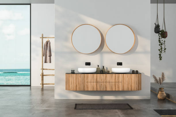 istock Modern bathroom interior with concrete floor, two sinks, double mirrors, white bathtub, interior plants, sea view from window.Minimalist bathroom with modern furniture and panoramic view. 3D rendering 1439610026