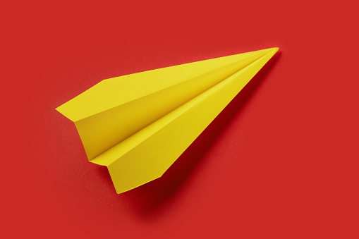 yellow paper airplane isolated on red background