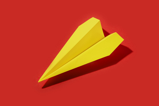 yellow paper airplane isolated on red background