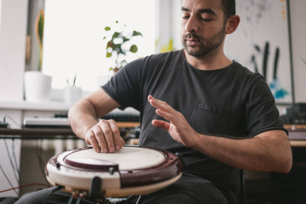 istock Young musician playing wavedrum percussion instrument in home music studio 1439610921