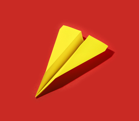 yellow paper airplane isolated on red background