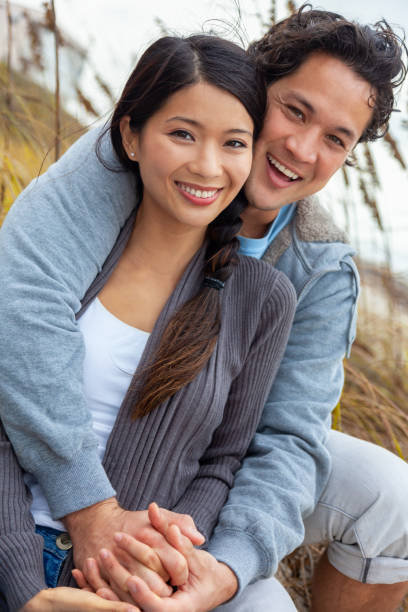 asiatischer mann frau romantisches lächelndes paar dating draußen - women cheerful vertical 20s stock-fotos und bilder