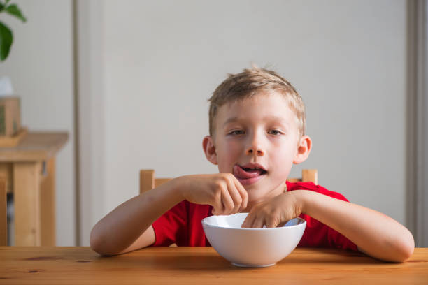 istock Cute boy eats granola for breakfast. Lifestyle portrait. 1439625162