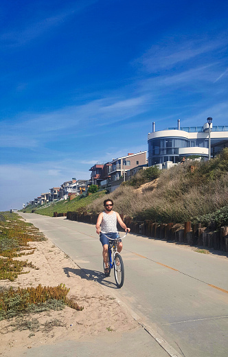 manhattan beach, united states - september 29 2015: person on bicycle on bike trail and expensive property on california coast