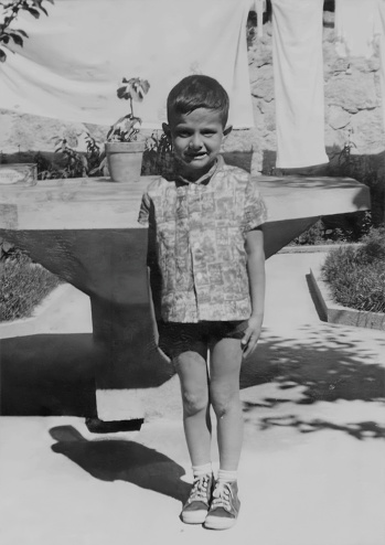 Black and white Image taken in the 60s, little boy standing looking at the camera