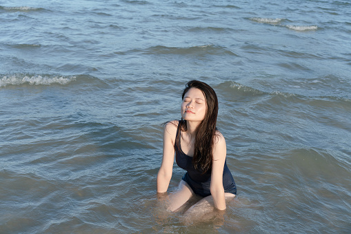 woman kneels in shallow seawater