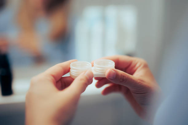 Hand Holding a Contact Lenses Case Filled with Disinfectant Solution stock photo