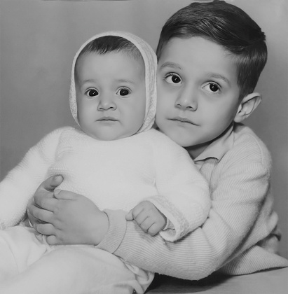 Black and white photo from the sixties, a little boy and a little girl posing together