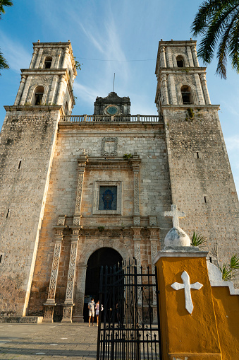 Yucatan, Mexico - April 15, 2021: Tourists leave the Templo de San Servacio, Catholic church with two stone bell towers originally dating from 1545 in Valladolid